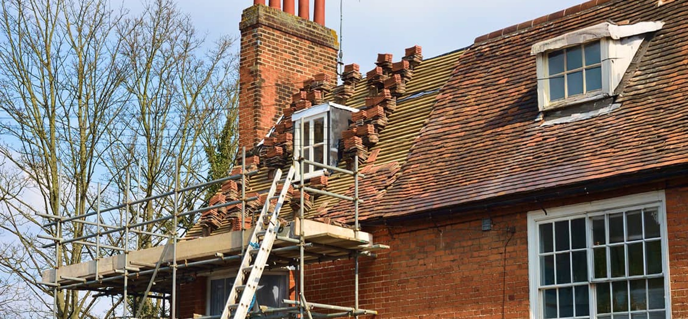 Brick house with roof repair scaffolding and ladder