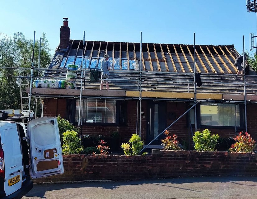Roofing crew replacing roof on house with scaffolding