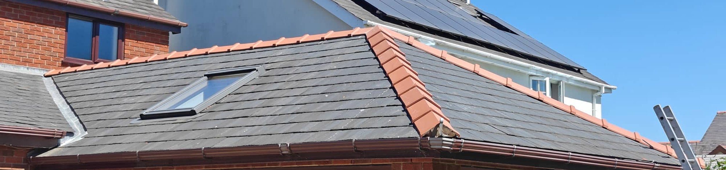 Residential roof with solar panels and skylight under blue sky