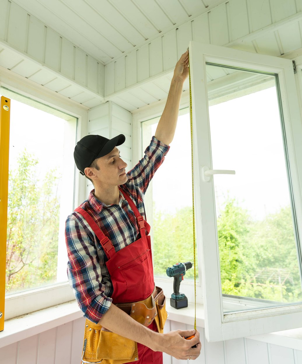 Contractor measuring window frame during installation