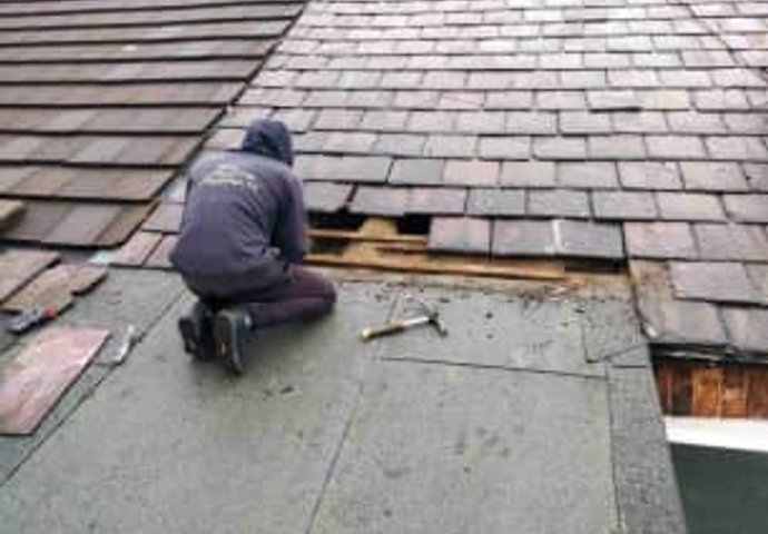 Roofer installing shingles on residential roof