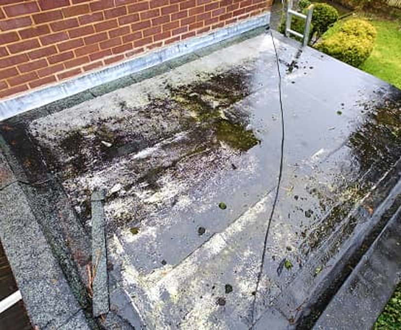 Weathered flat roof with moss and damage